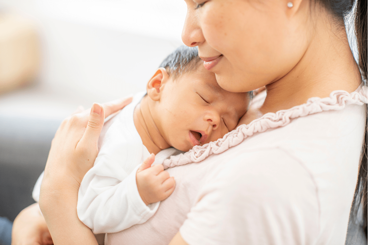 young Asian mom holding newborn baby (must haves for new moms)