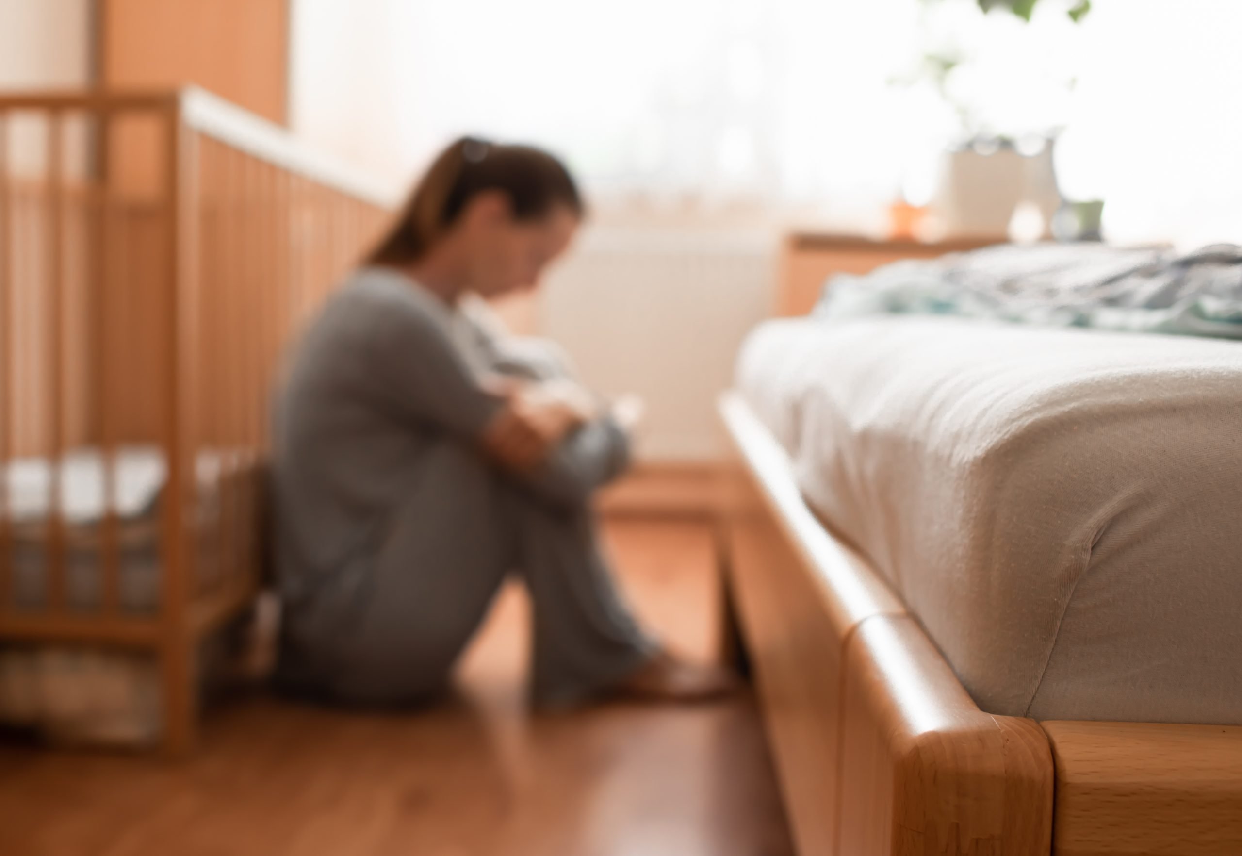 woman with postpartum depression sitting by empty crib