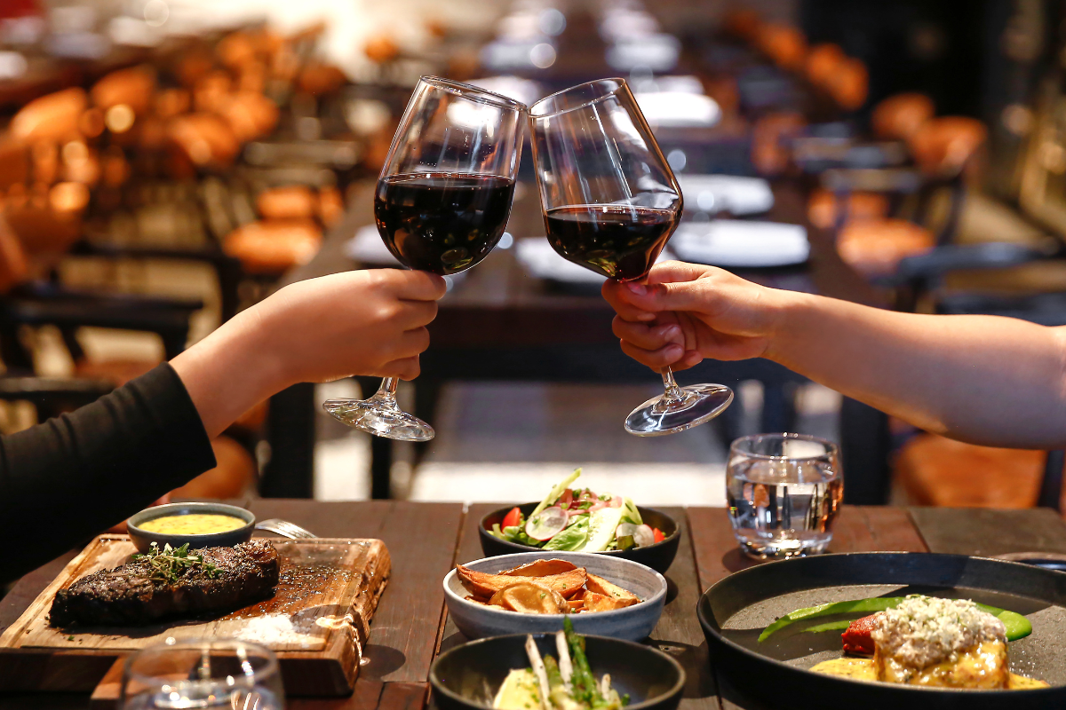 couple holding wine glasses at a restaurant, toasting their date night in the city