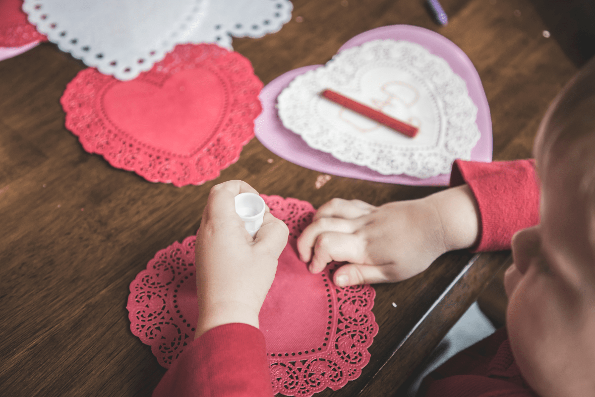 child making a paper valentine (how to celebrate Valentine's Day with kids)