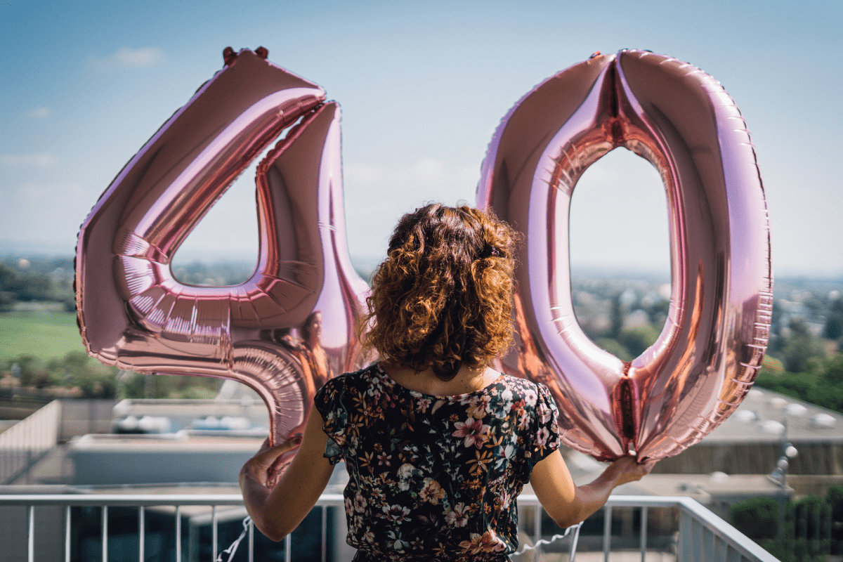 woman holding "40" balloons to celebrate her 40th birthday