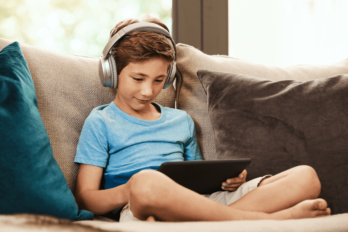 child wearing headphones and holding iPad (YouTube channels for kids)