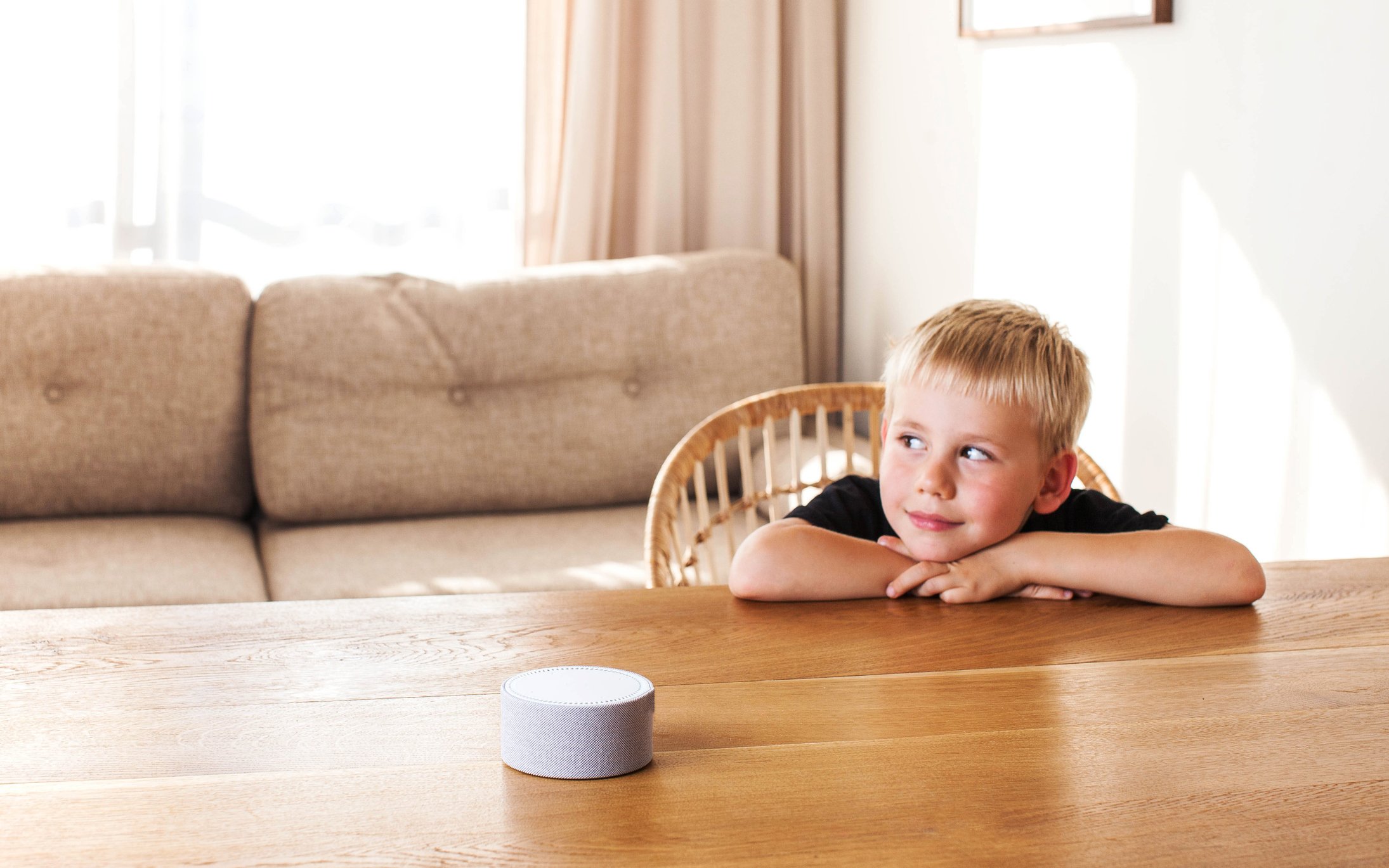 Cute boy sitting at the dining table and listening to the smart speaker. (Alexa Skills for kids)