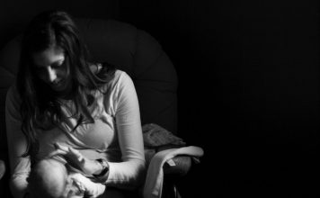 black and white photo of a mother looking at her new baby