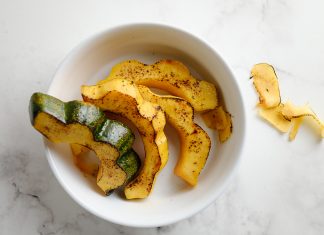 roasted and seasoned slices of acorn squash in a white bowl on a countertop