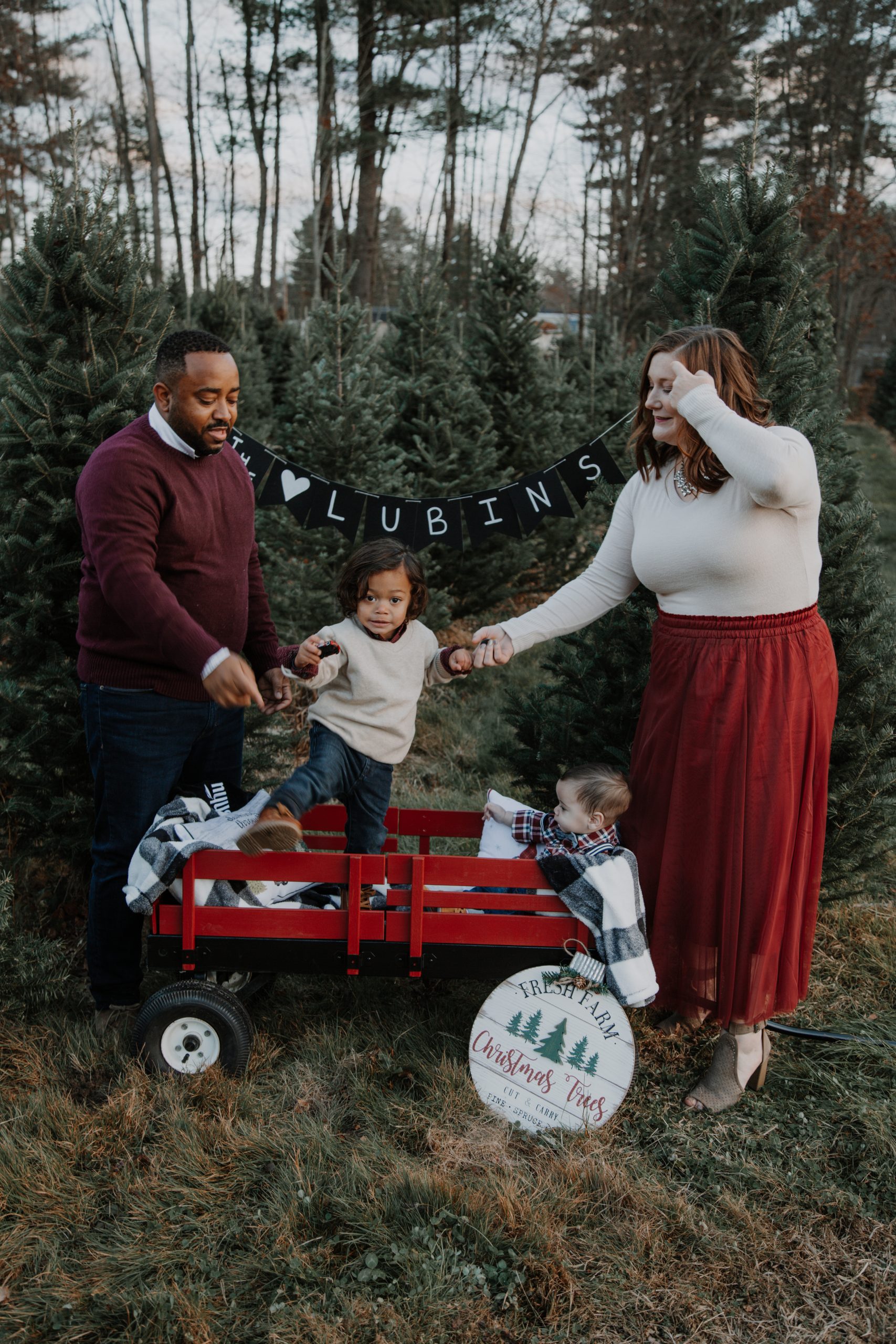 Family photo for holiday cards including mom and dad trying to wrangle two toddlers climbing out of a wagon