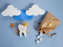 white wooden tooth with a drawn-on smile, wearing a crown and holding a star wand