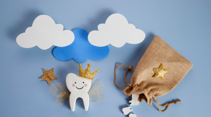 white wooden tooth with a drawn-on smile, wearing a crown and holding a star wand