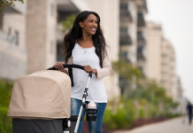 Black woman smiling while pushing a stroller down a city street