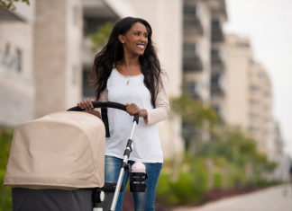 Black woman smiling while pushing a stroller down a city street