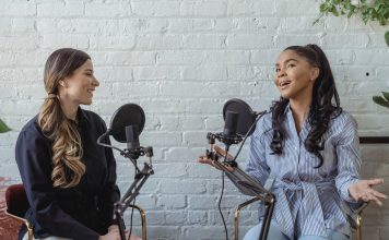 two women speaking into microphones, recording a podcast episode