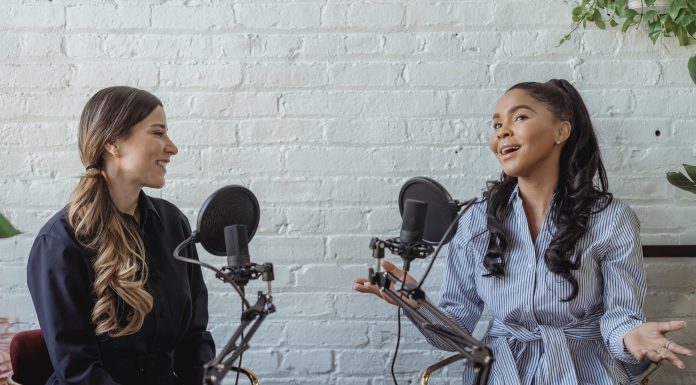 two women speaking into microphones, recording a podcast episode