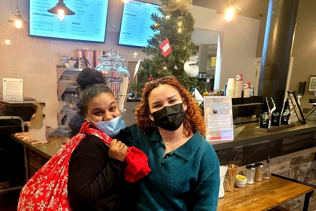two females standing in a cafe, with face masks