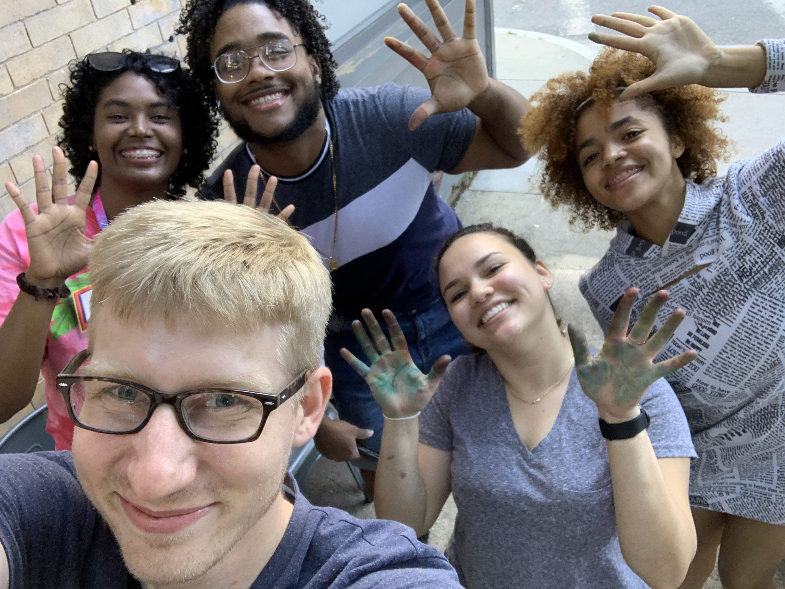 5 people in a selfie, with their hands stained by tye dye