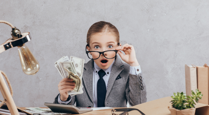 Child, in a business suit with glasses, holding money. She is surprised.