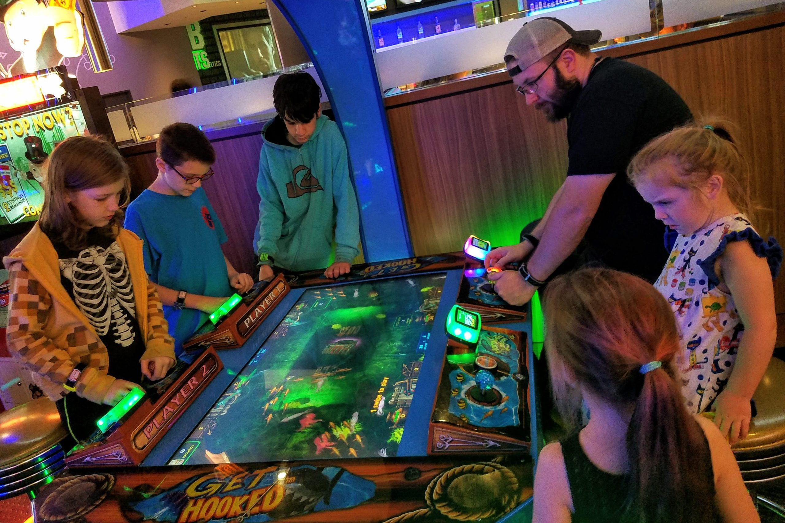 family with teenagers enjoying arcade games in Boston