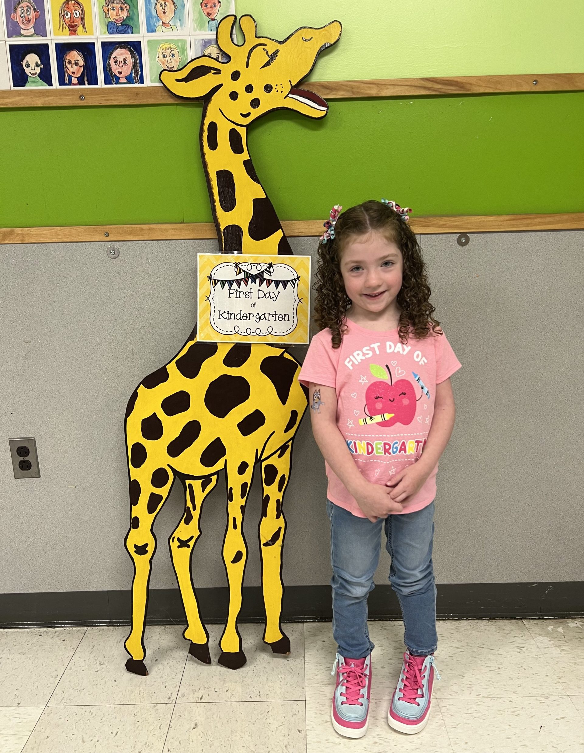 girl standing next to paper giraffe on the first day of elementary school