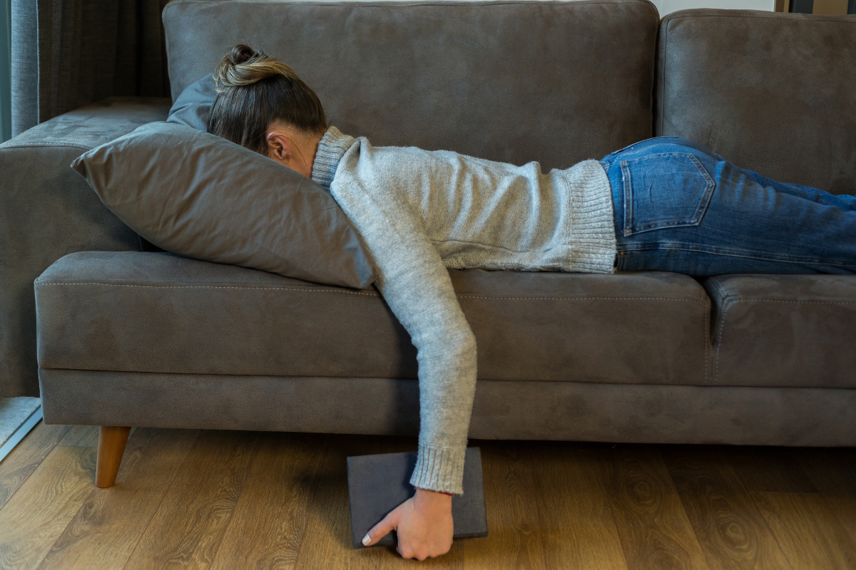 woman lying on the couch, face down in a pillow, suffering from chronic illness (idiopathic hypersomnia)
