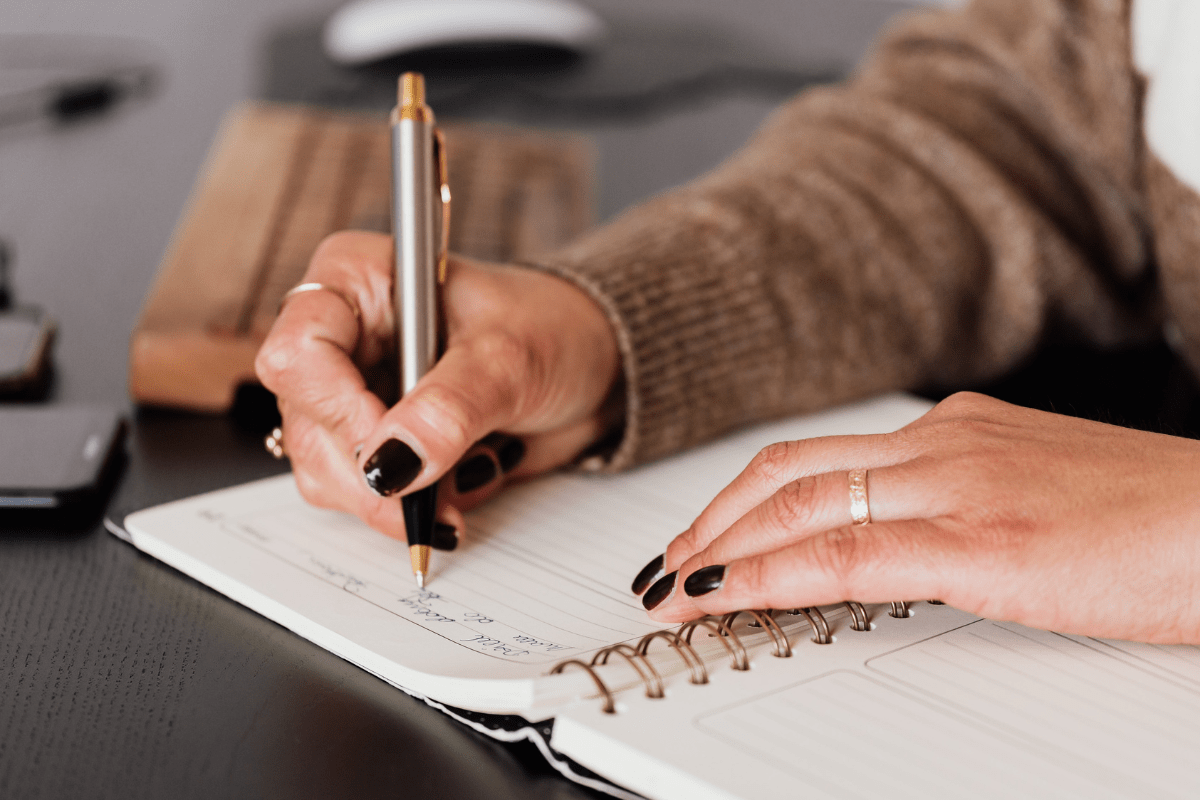 woman writing in a planner (2024 planners for busy moms)