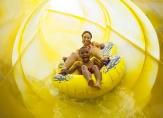 mother and son on a yellow tube sliding down a yellow waterslide at Great Wolf Lodge in Fitchburg, one of New England's indoor water parks