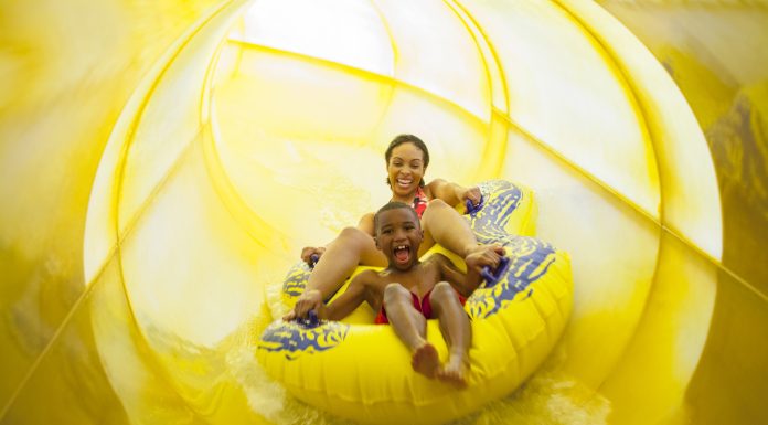 mother and son on a yellow tube sliding down a yellow waterslide at Great Wolf Lodge in Fitchburg, one of New England's indoor water parks