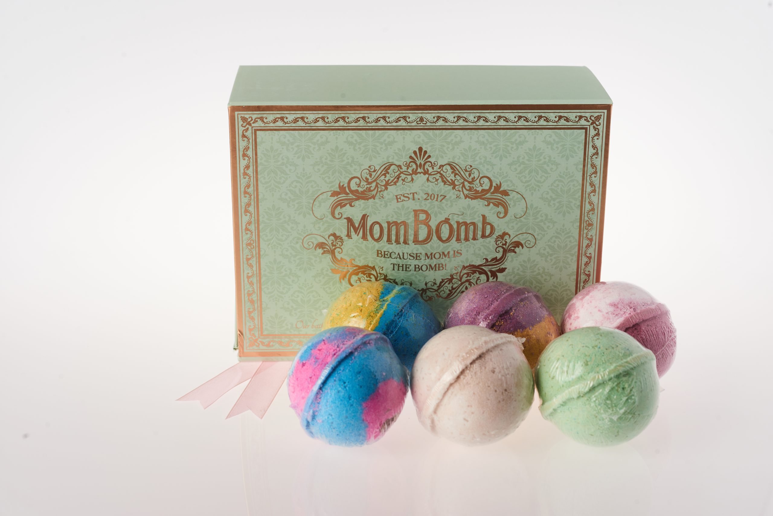 six bath bombs sitting in front of a box with the Mom Bomb logo