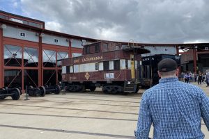 Walking through the train yard at Steamtown in Scranton, PA. An Erie Lackawanna caboose is outside of a train shed.