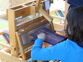 girl at weaving loom at Gore Place Sheepshearing Festival during April school vacation week