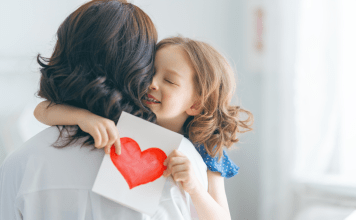 child giving mom a card and hug for Mother's Day