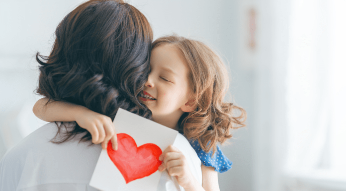 child giving mom a card and hug for Mother's Day