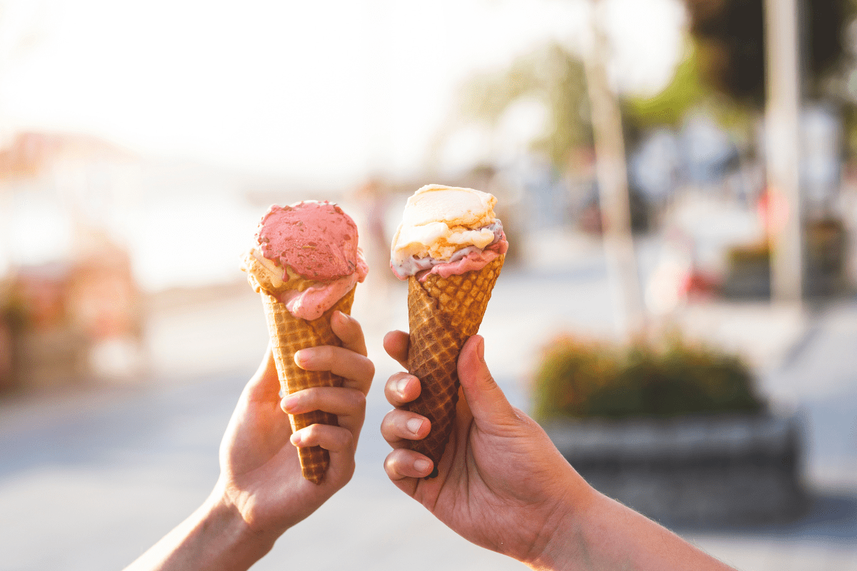two hands holding two cones of gelato