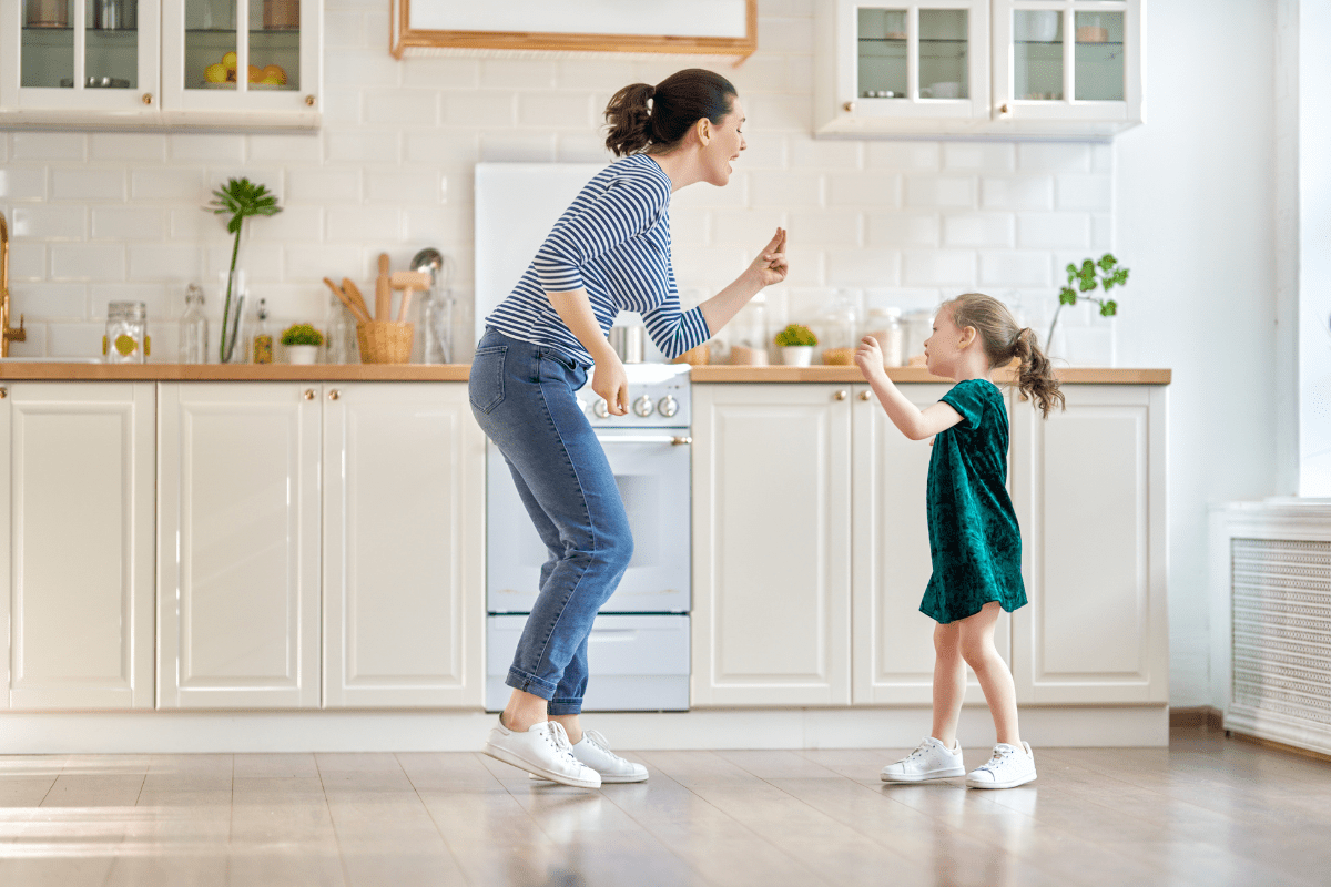 mom and daughter dancing and singing in the kitchen