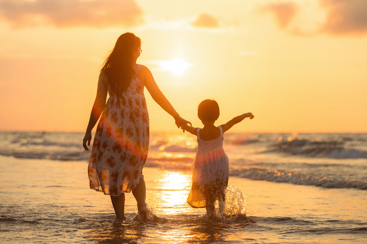 mother and child standing in the shallow waves at the beach