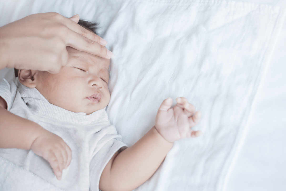 mother checks baby's forehead for fever (febrile seizures)