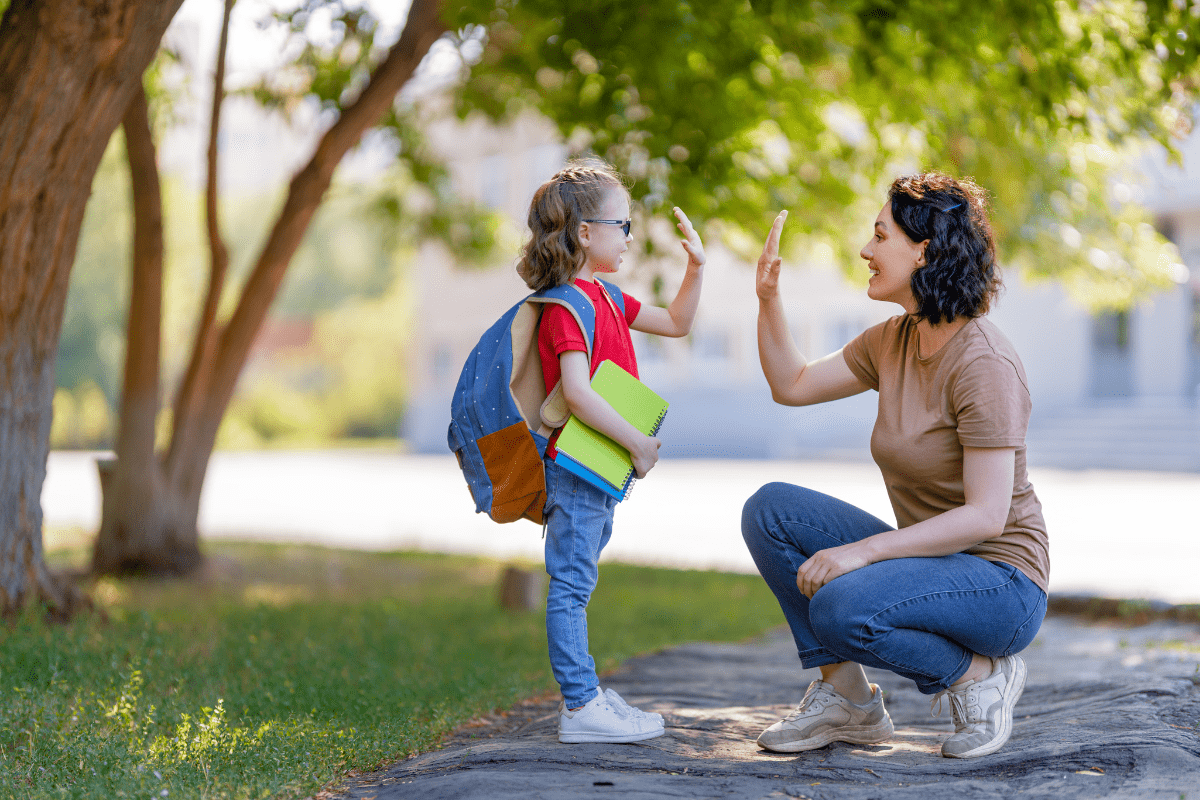 mom and child high-fiving after school (questions to ask your child after school)