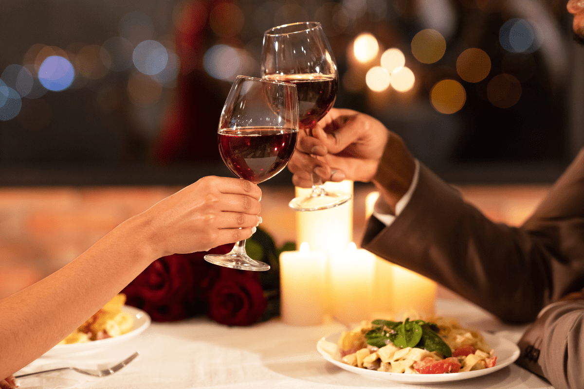 couple holding wine glasses at restaurant (date night restaurants north of Boston)